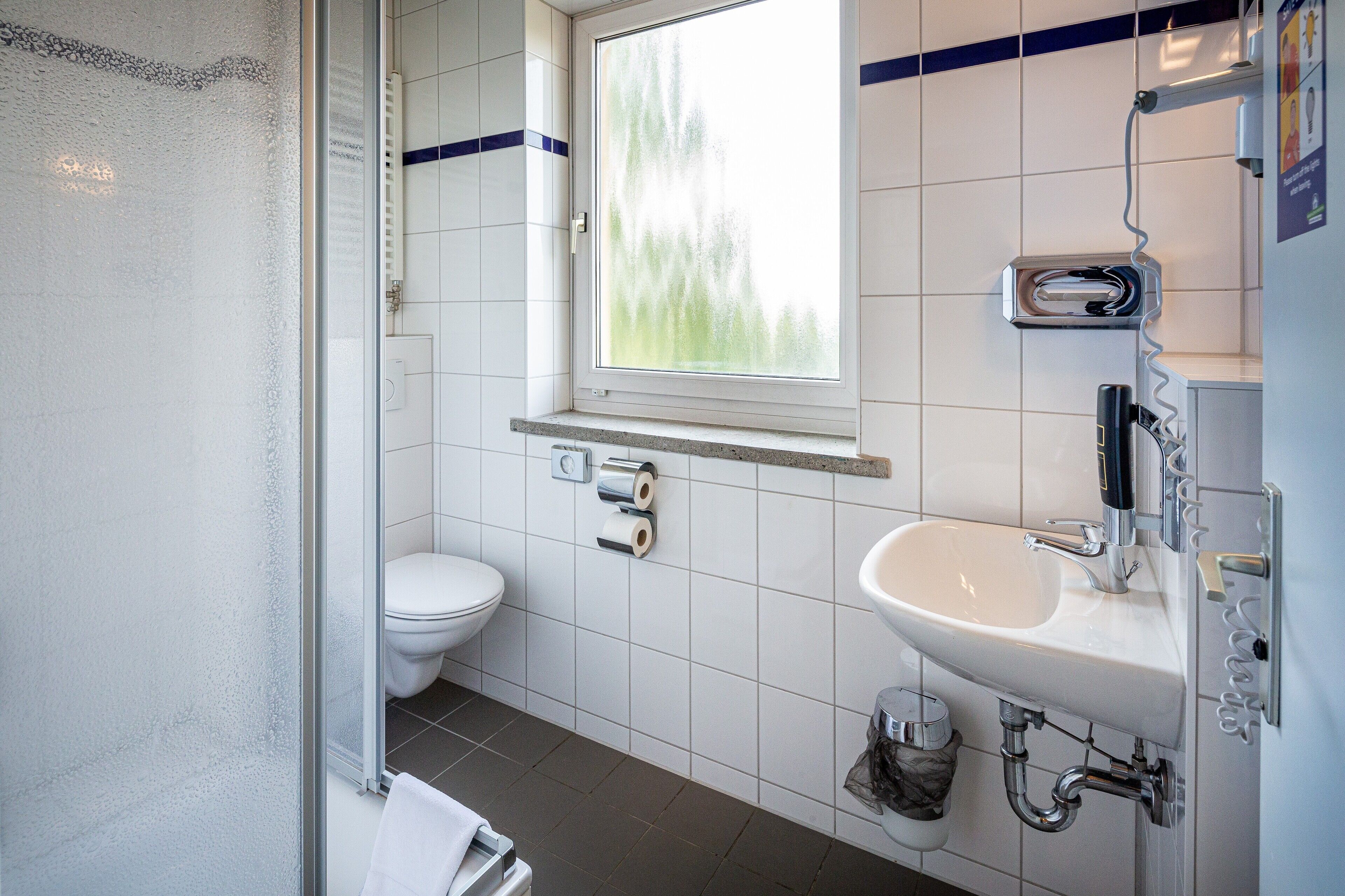 A modern bathroom with a toilet, sink, and shower.