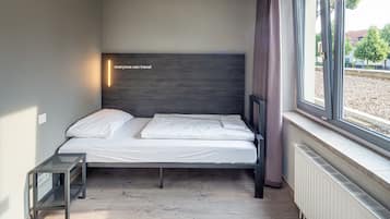 Een moderne slaapkamer met een bed, een klein nachtkastje en een raam met uitzicht op de omgeving.