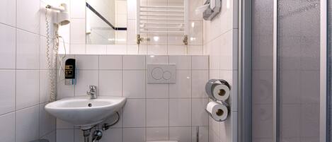 Un baño moderno con lavamanos, inodoro y ducha blancos.