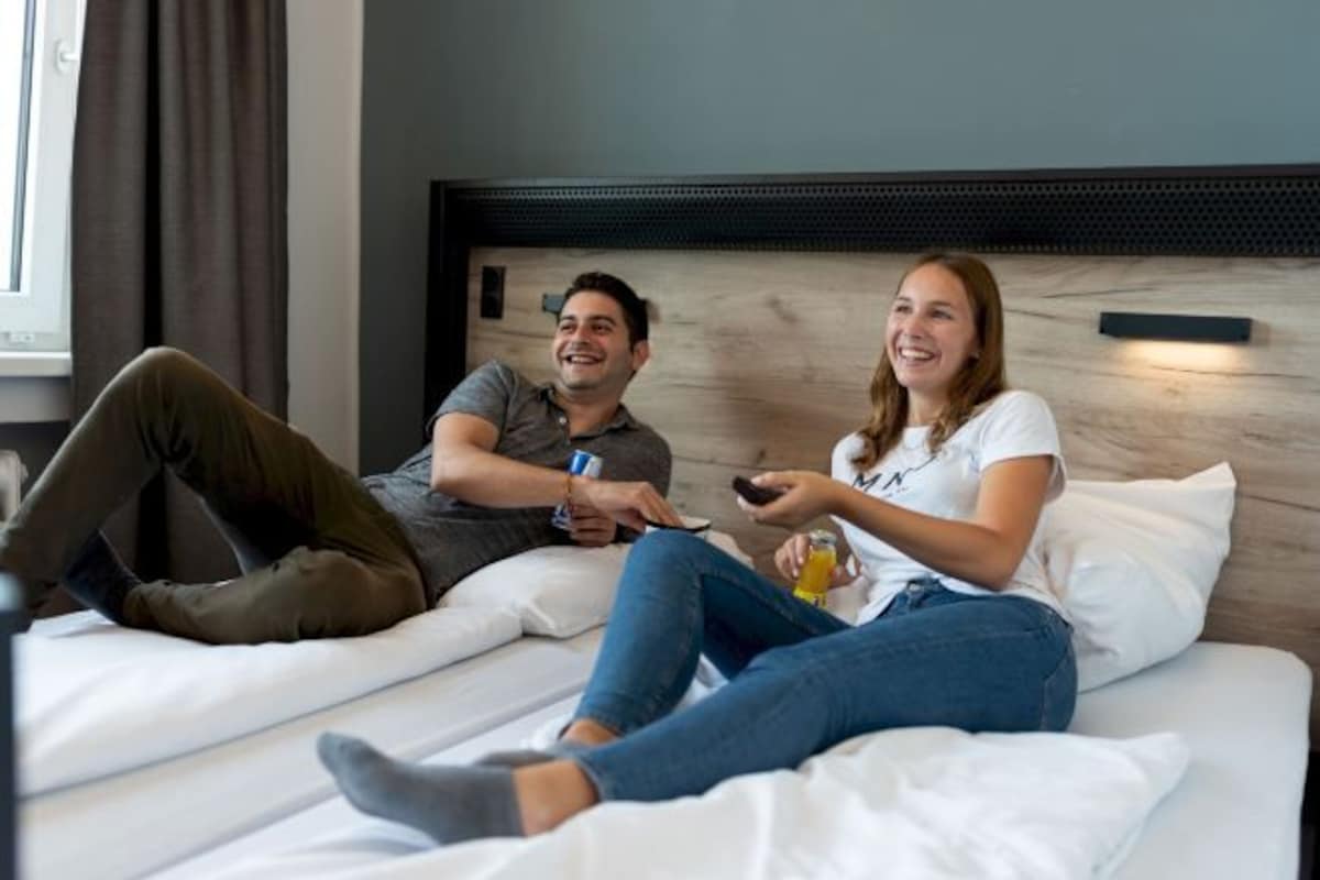 Une chambre d’hôtel avec un lit, une tête de lit et une fenêtre avec des rideaux.