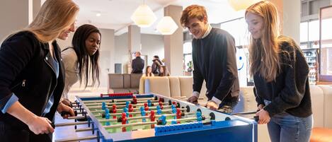 Un grupo de personas jugando al fútbol de mesa en un espacio interior bien iluminado con mobiliario moderno y ambiente relajado.