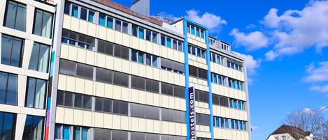 A multi-story building with a modern architectural design, featuring a prominent 'a&o' sign on the ground floor, indicating a commercial space.