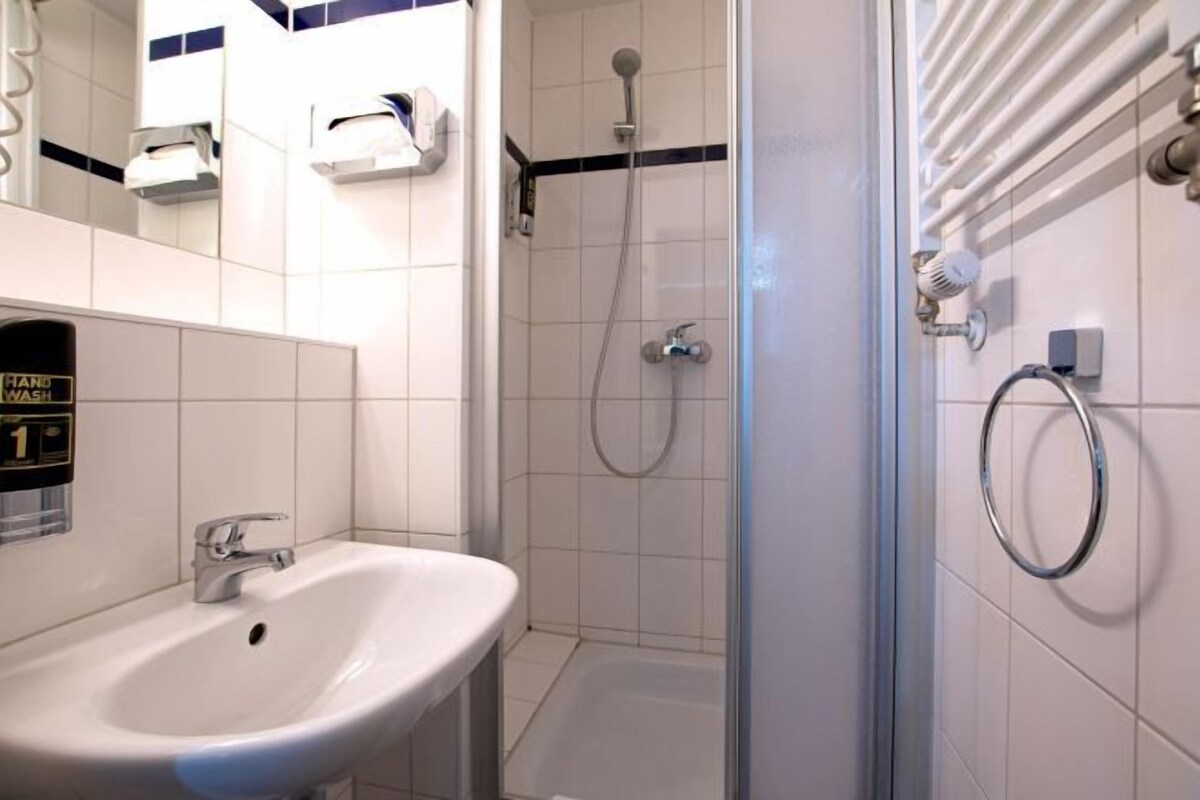 A bathroom with a sink, a shower, and a hand wash station.