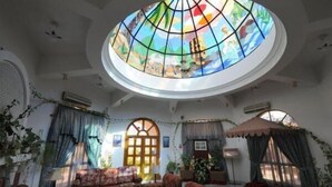 Una habitación con un amplio ventanal de vitral, un conjunto de sofás y una televisión.