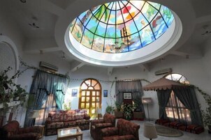 Una habitación con un amplio ventanal de vitral, un conjunto de sofás y una televisión.