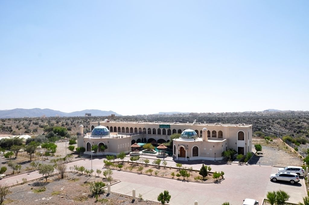 A large building with a central courtyard, arched walkways, and two prominent domes.