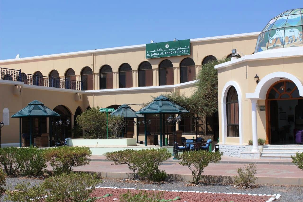 The exterior of Al Jabal Al Akhdhar Hotel with a courtyard, outdoor seating, and a large glass dome structure.