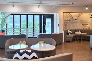 A modern lounge area with seating, a small table, and a view through large windows.