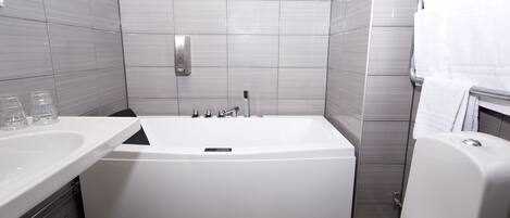 Un baño moderno con una bañera independiente, inodoro y lavamanos.