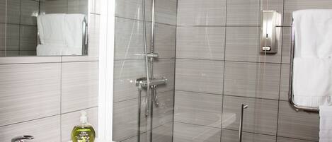 A modern bathroom with a glass-enclosed shower, a white sink, and a mirror.