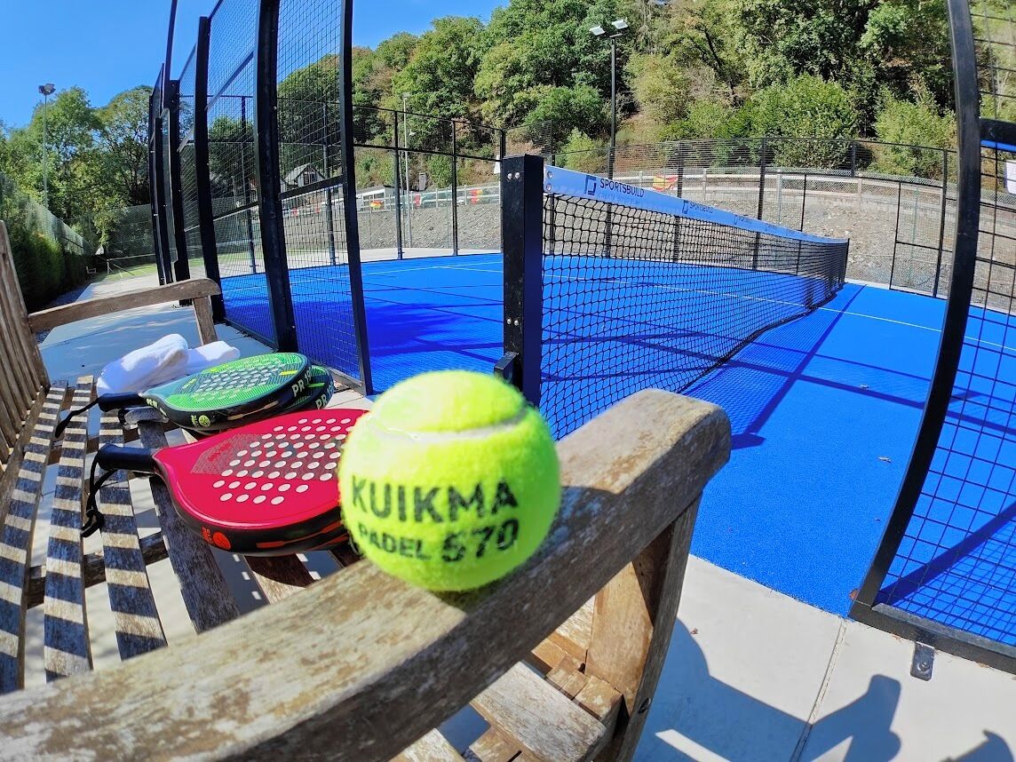 Instalación deportiva con piso azul, red de tenis y valla de madera.