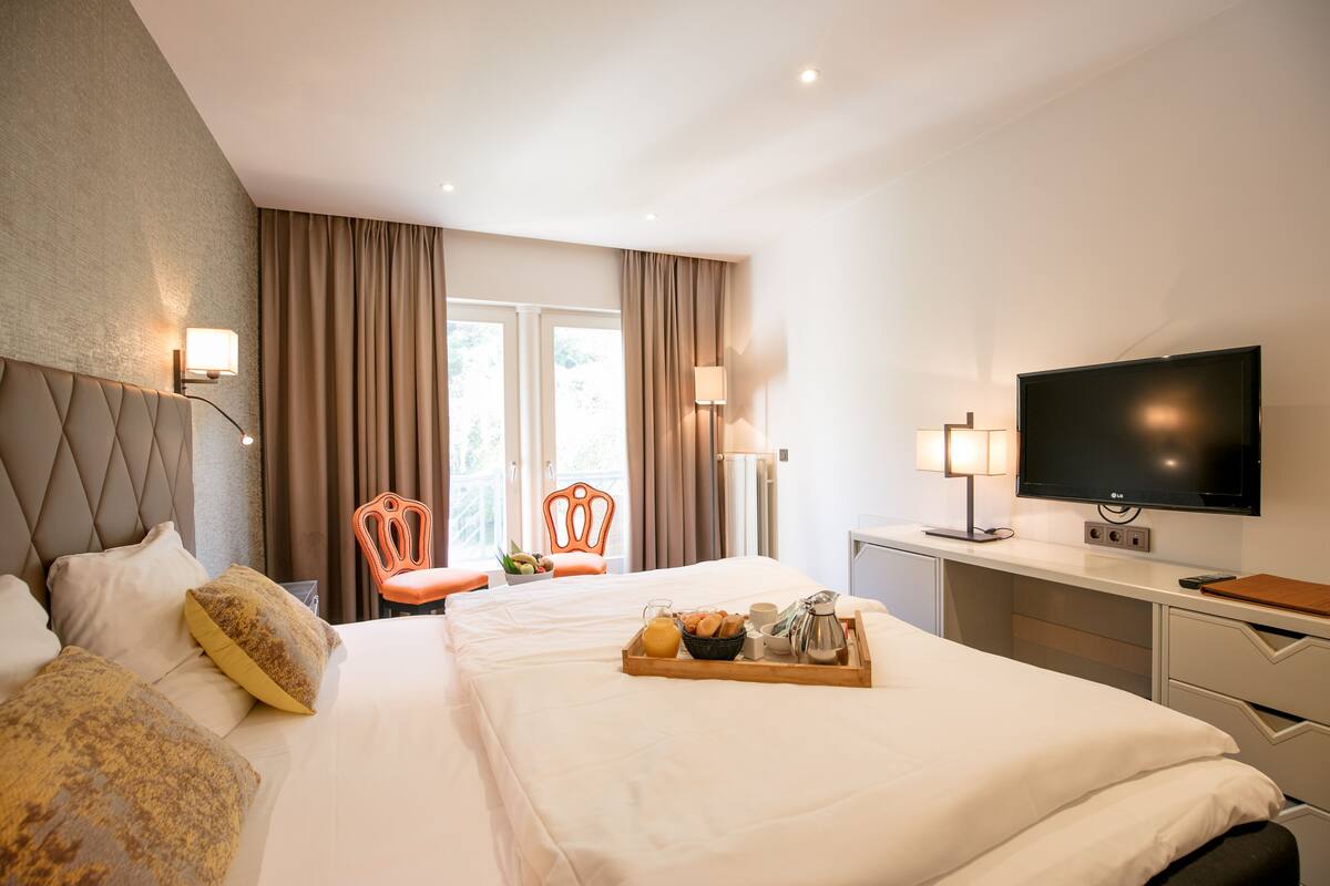 A hotel room with a bed, a desk, a TV, and a breakfast tray.