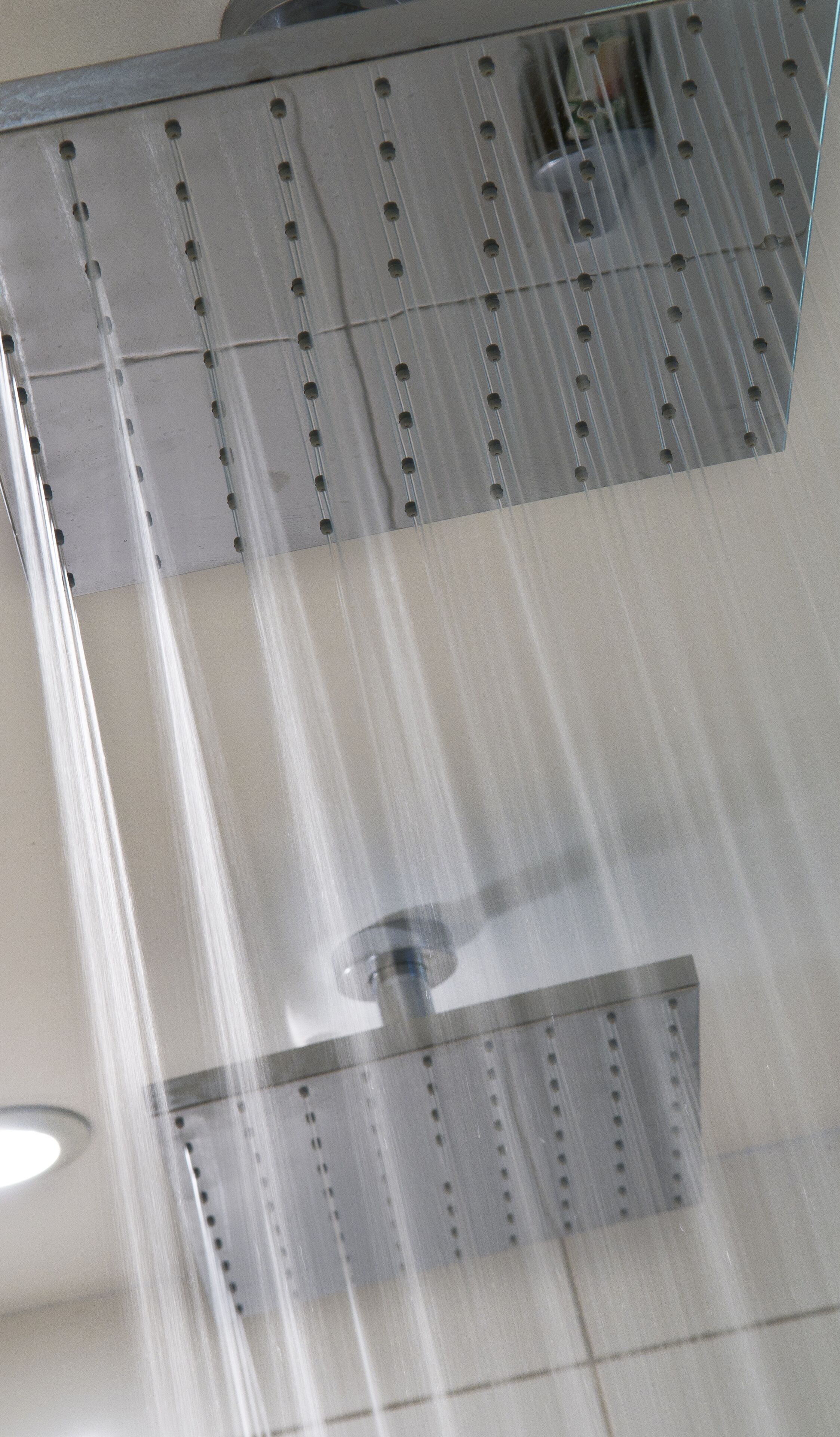 A shower with a metal grate and water flowing down.