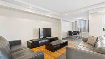 A modern living room with a flat-screen TV, leather sofas, and a wooden coffee table.
