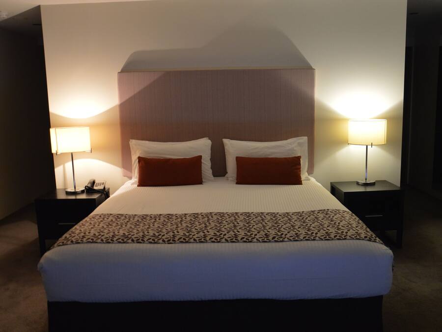 A hotel room with a large bed, two bedside tables, and two lamps.