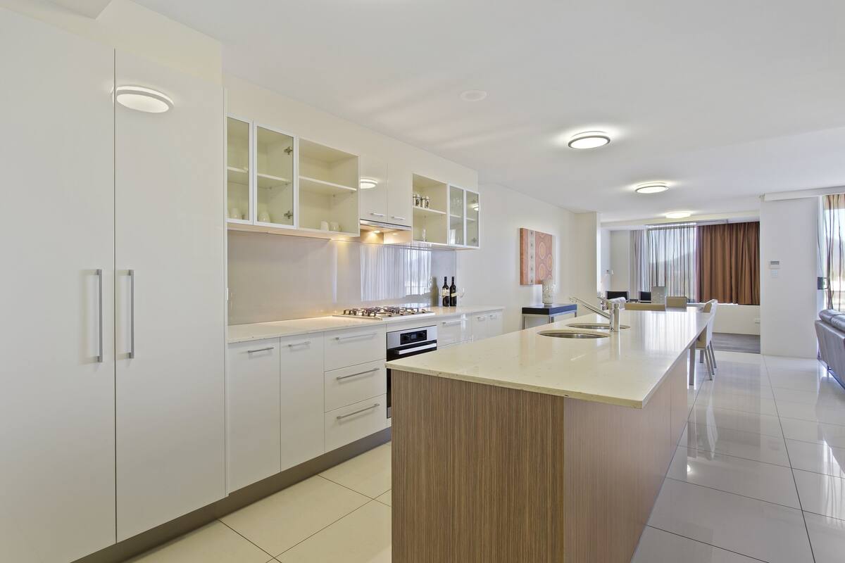 A modern kitchen with white cabinets, a central island, and built-in appliances.