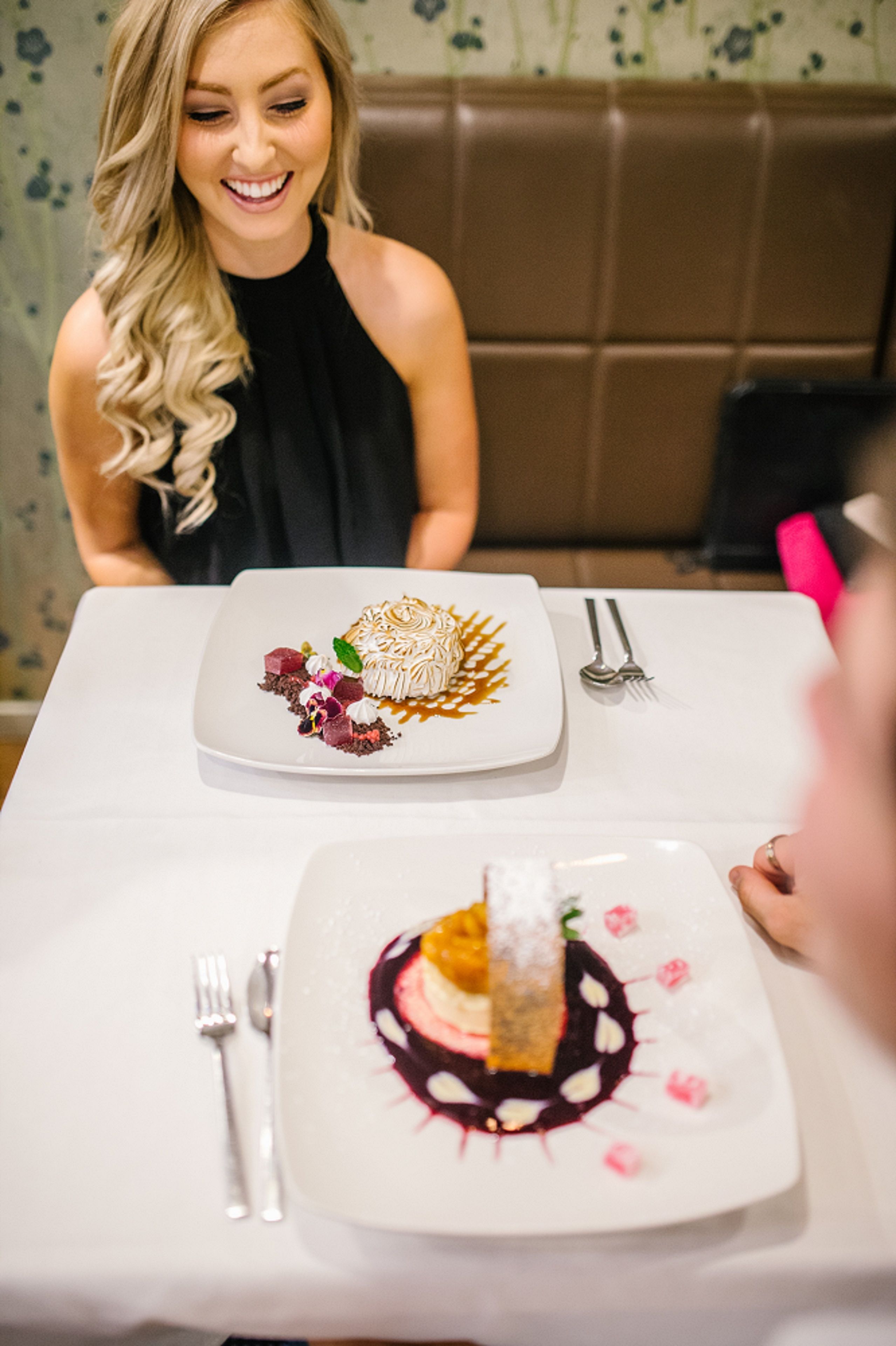 A dining table with two plates of food, a fork, and a spoon.