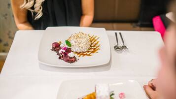 A dining table with two plates of food, a fork, and a spoon.
