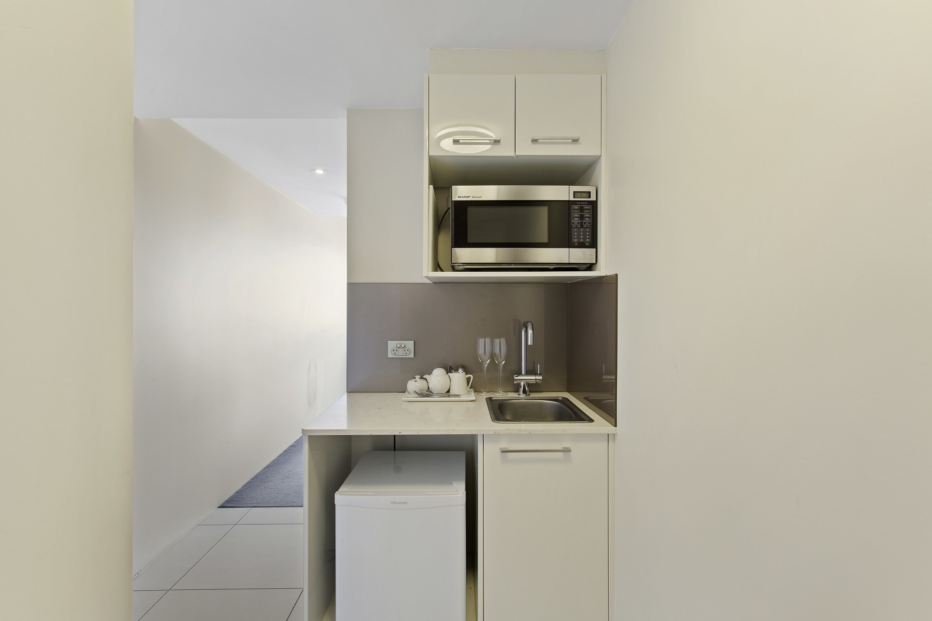 A compact kitchen with a built-in microwave, a sink, and a small refrigerator.