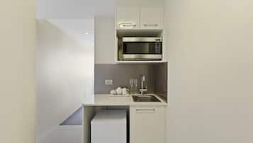 A compact kitchen with a built-in microwave, a sink, and a small refrigerator.