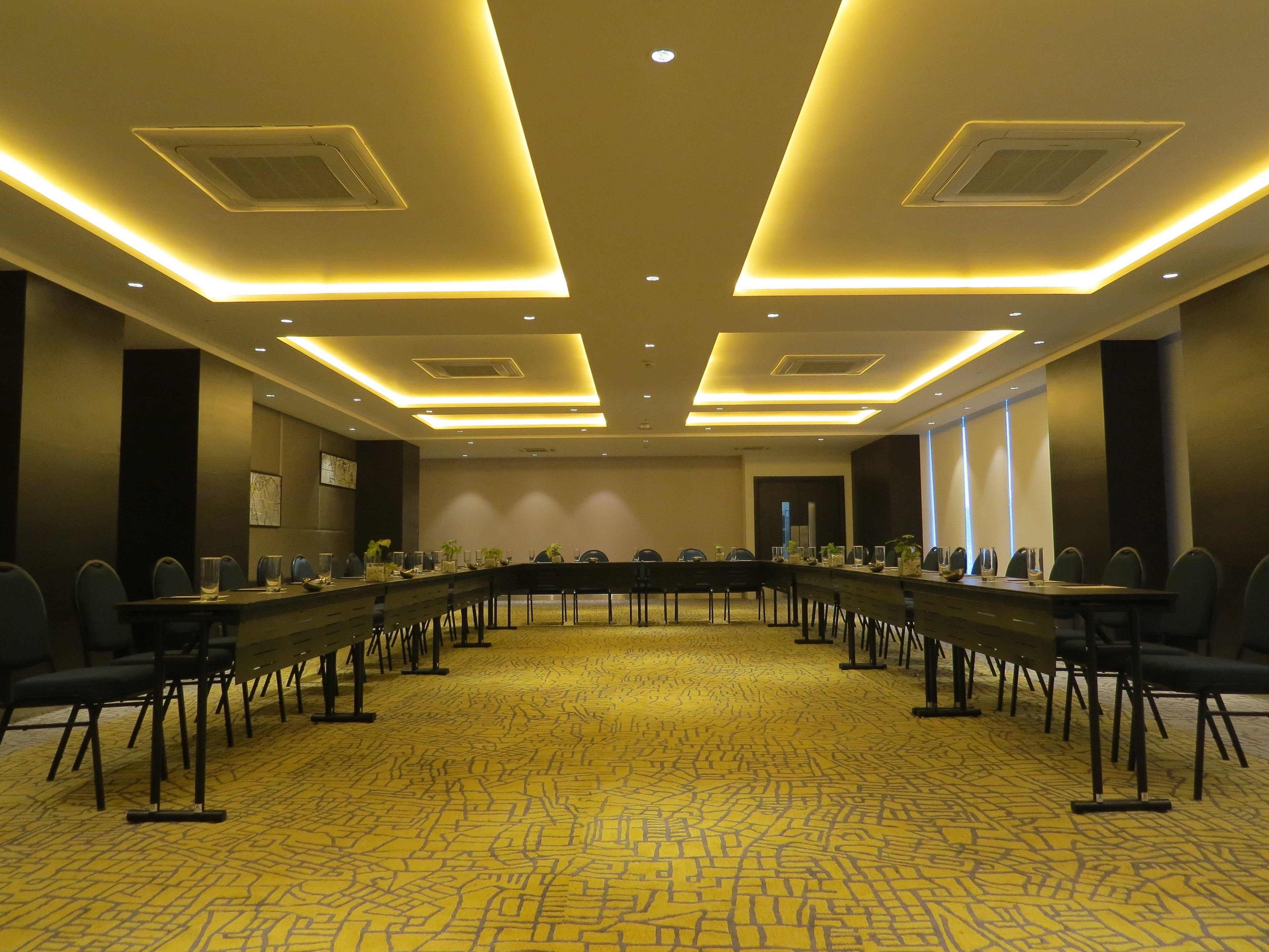A conference room with a long table, chairs, and a patterned carpet.