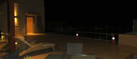 Terraza en la azotea con sillones, una mesa y plantas en macetas.