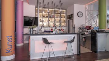 A modern kitchen with a bar area, including a refrigerator, oven, and coffee machine.