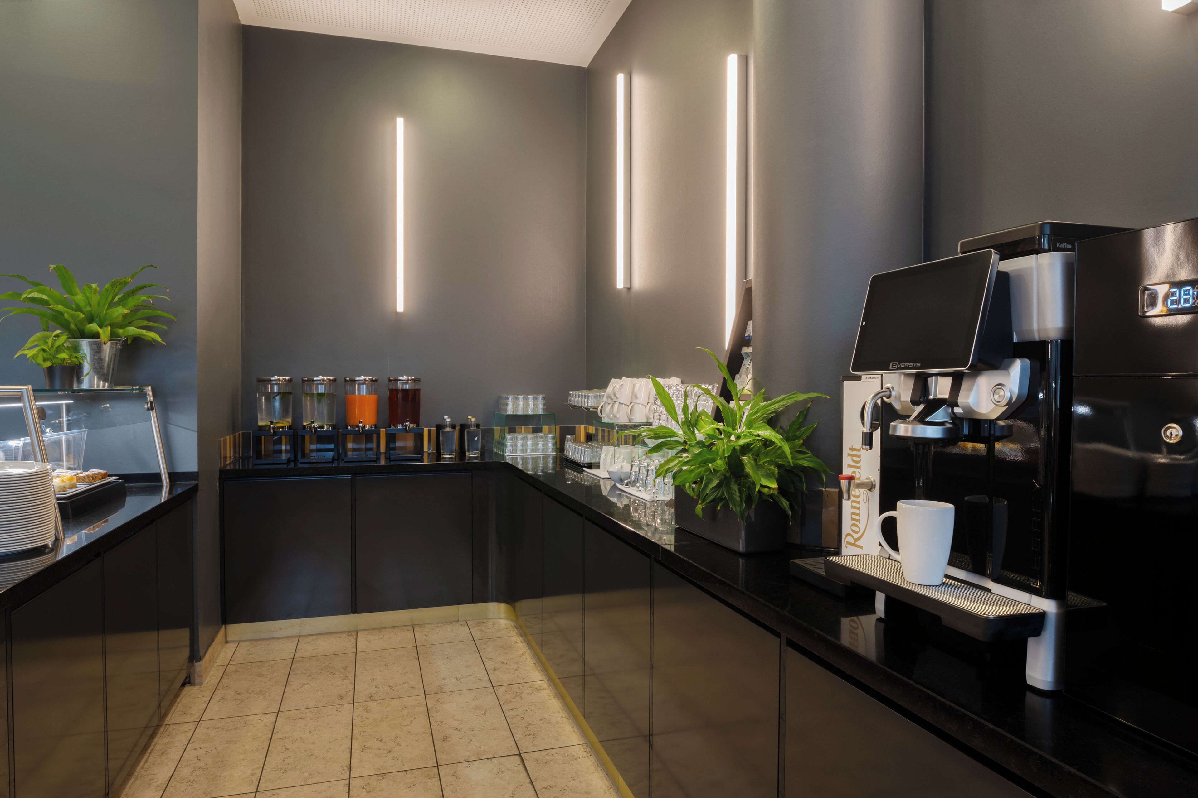 A modern coffee station with a sleek black counter, a coffee machine, and various coffee dispensers.