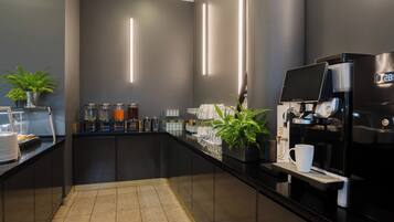 A modern coffee station with a sleek black counter, a coffee machine, and various coffee dispensers.