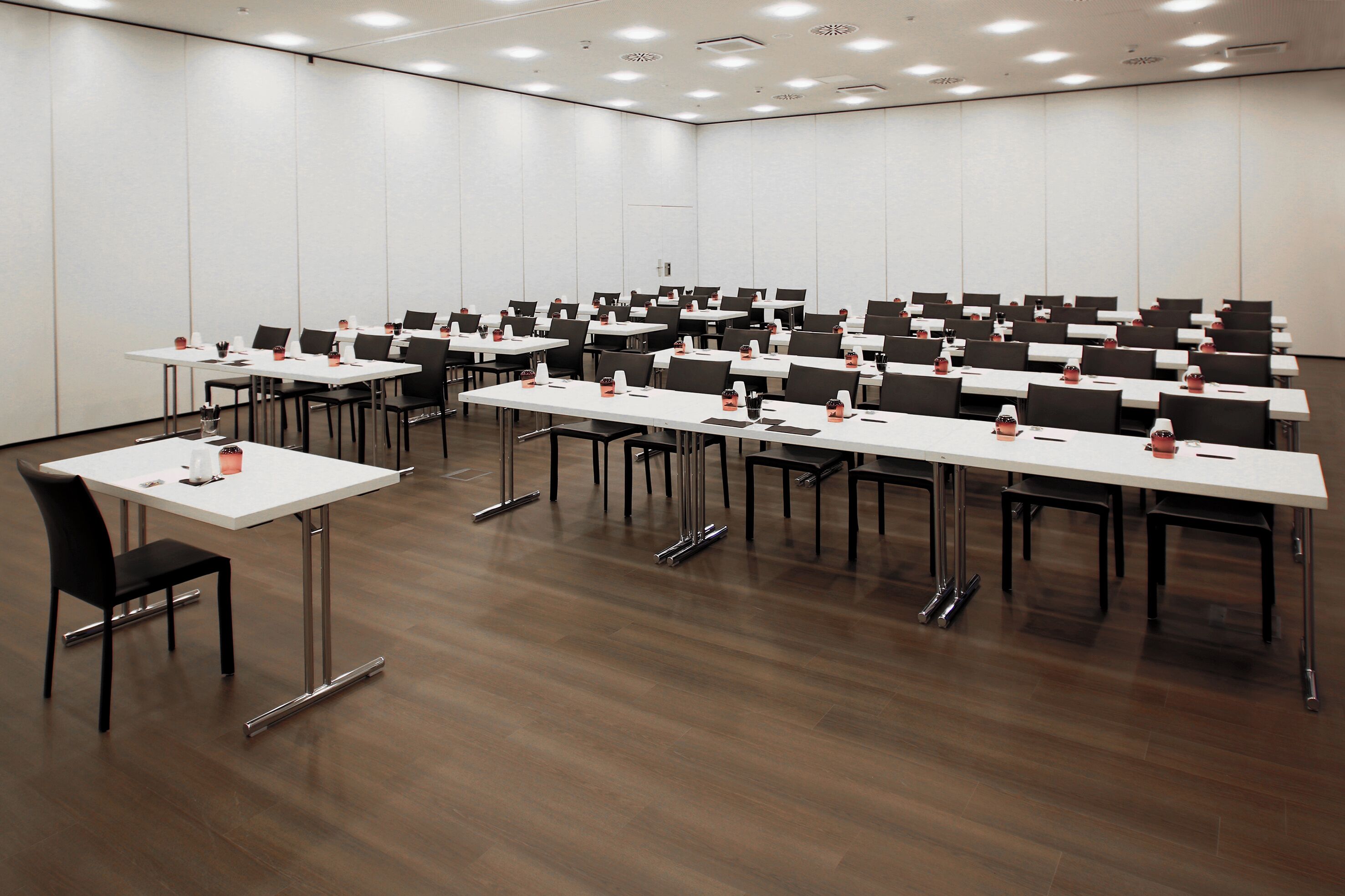 Ein Konferenzraum mit mehreren Tischen und Stühlen, ausgestattet mit Namensschildern und Wasserflaschen.