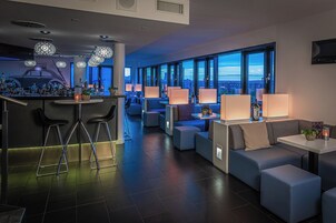 A modern bar area with stools, bar counter, and ambient lighting.