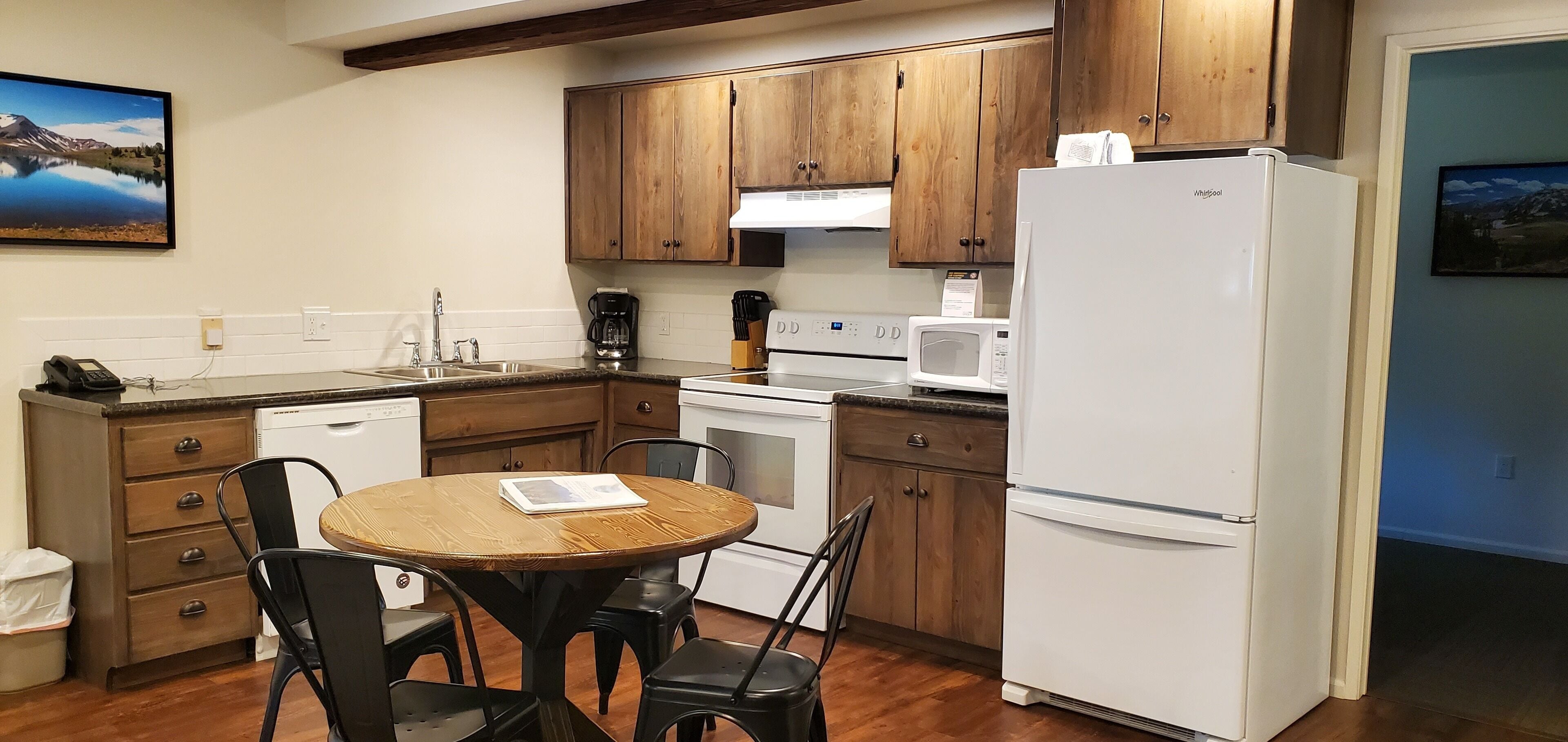 Una cocina compacta con armarios de madera, un refrigerador blanco, un microondas y una cafetera.