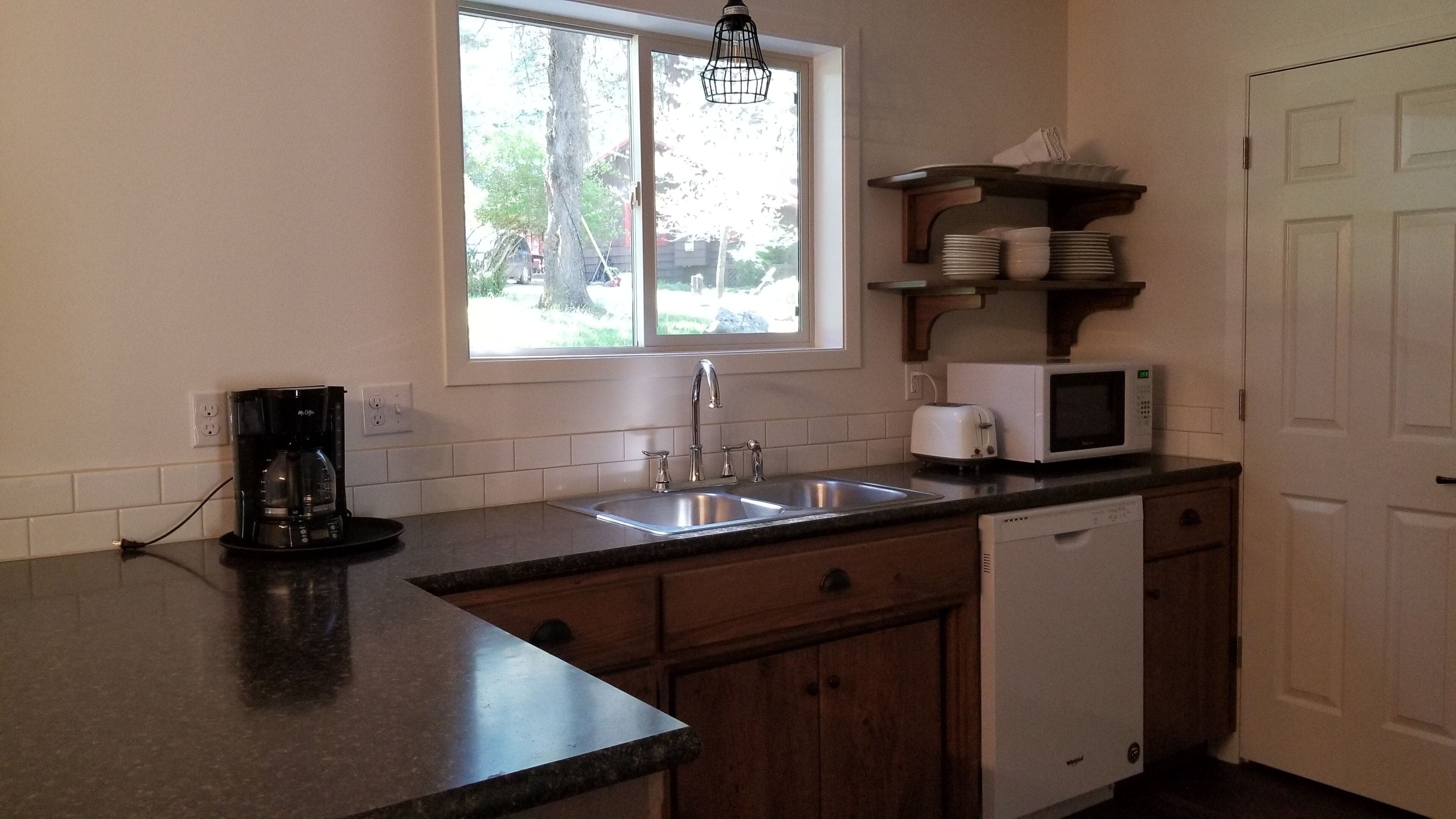 A kitchen with a window, a coffee maker, a microwave, and a dishwasher.