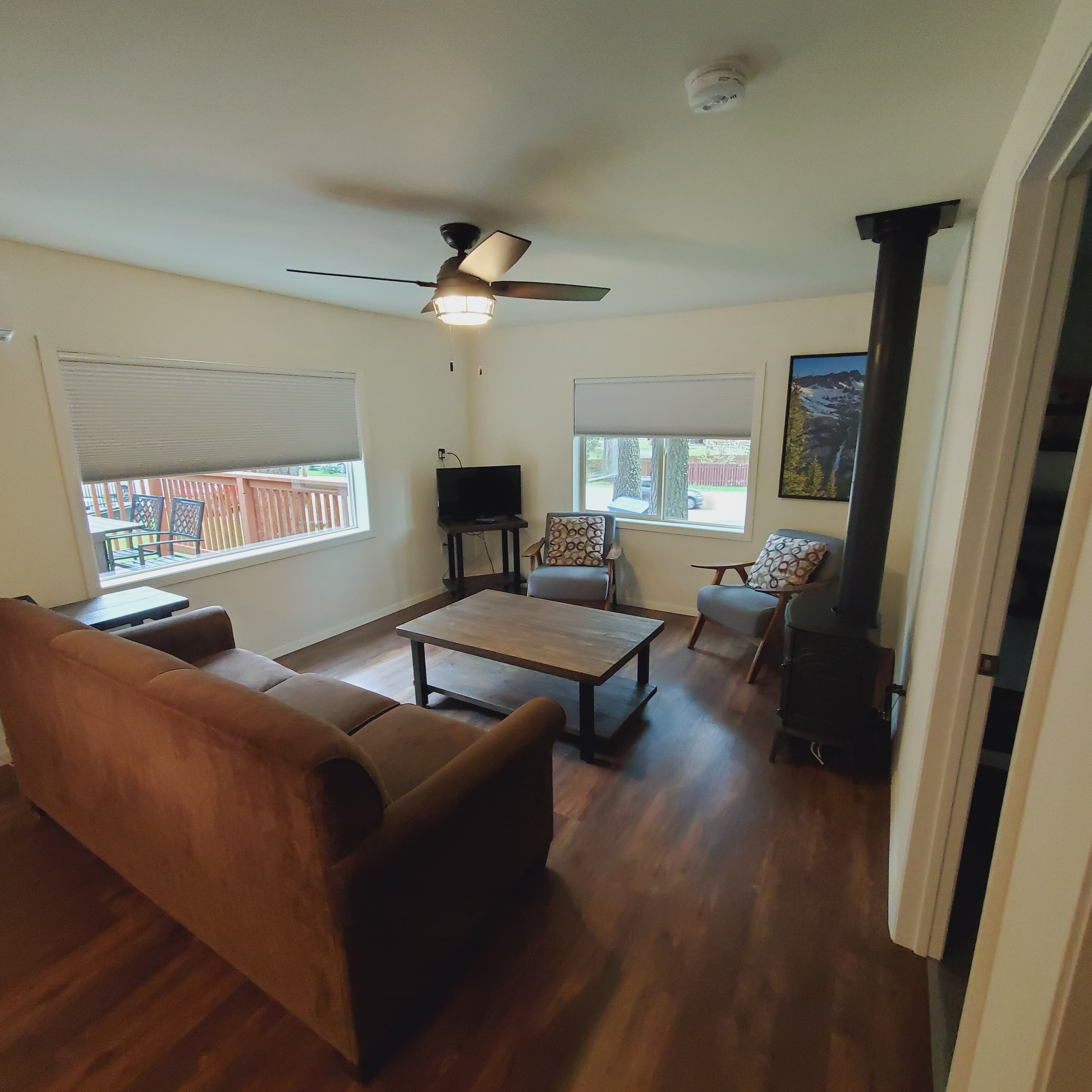 Ein Wohnzimmer mit Deckenventilator, Fernseher und Kamin.