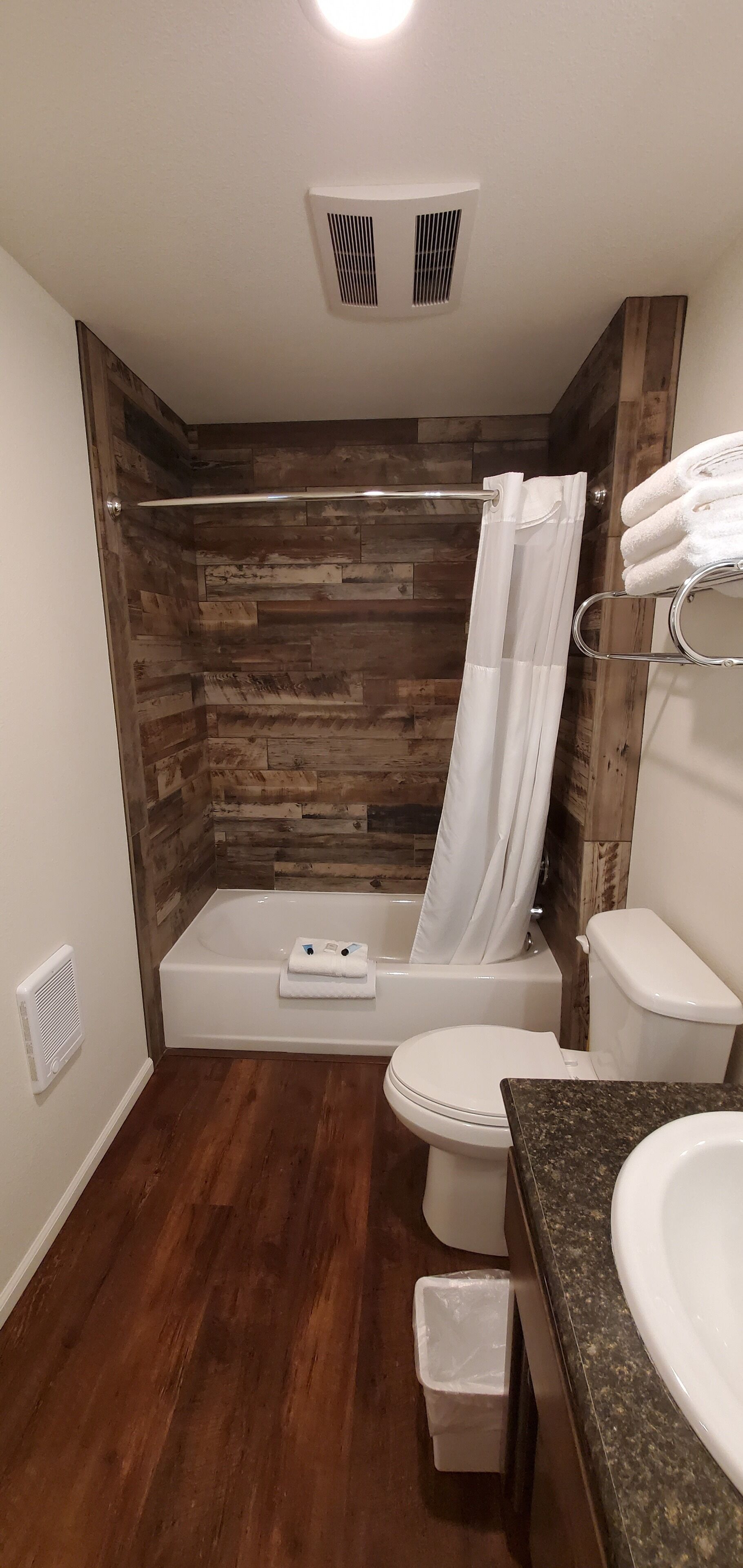 A bathroom with a wooden wall, a bathtub, a toilet, and a sink.