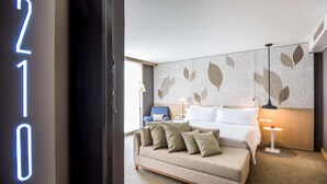 Moderni hotellihuone, jossa on sänky, sohva ja yöpöytä.