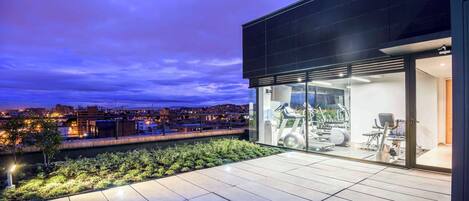 Un edificio moderno con fachada de vidrio y equipo de gimnasia al aire libre visible a través de las ventanas.