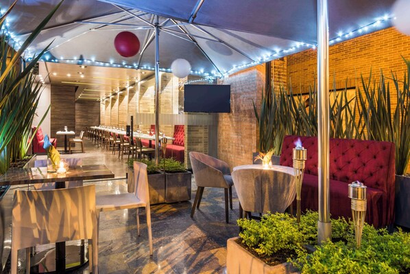 Un espace de restauration en plein air avec des tables et des chaises, un canapé rouge et un éclairage décoratif.