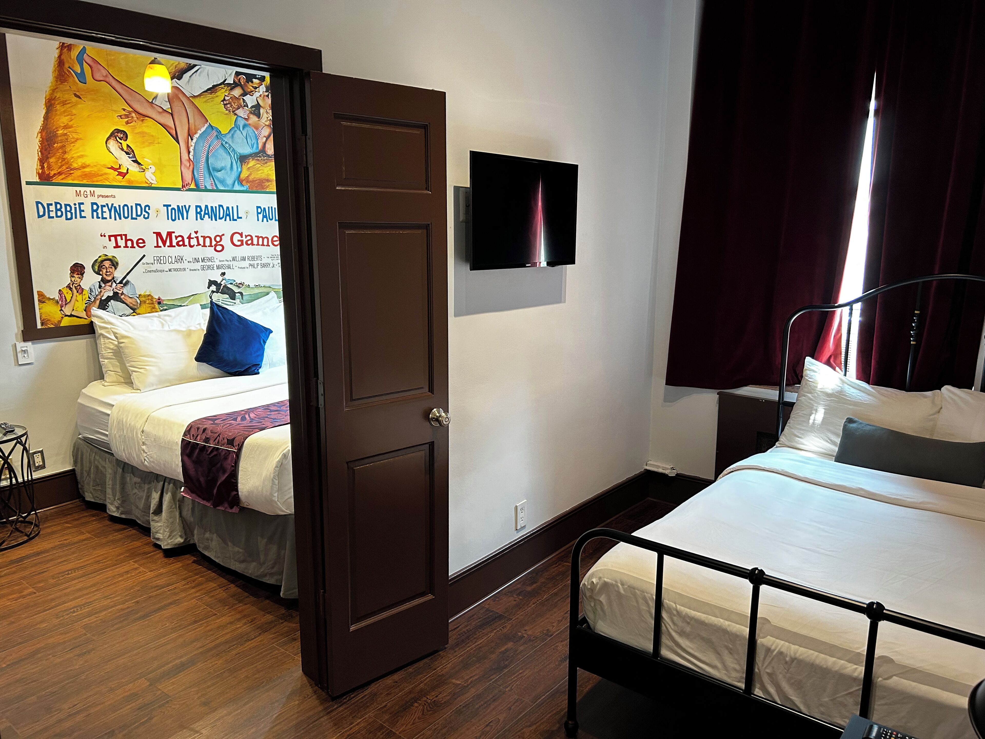 Ein Schlafzimmer mit zwei Betten, einem Fernseher an der Wand und einem Poster.