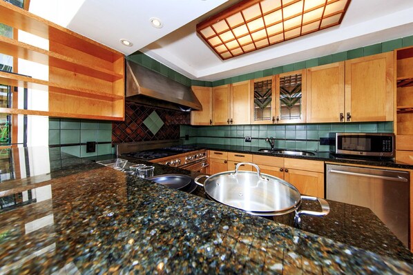 A modern kitchen with granite countertops, stainless steel appliances, and wooden cabinets. - Chelsea Pines Inn (New York)