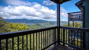Una terraza de madera con vistas a montañas y árboles.