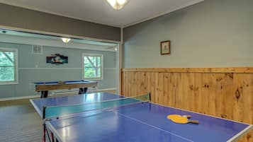 Quarto com mesa de pingue-pongue, mesa de bilhar e parede revestida em madeira.