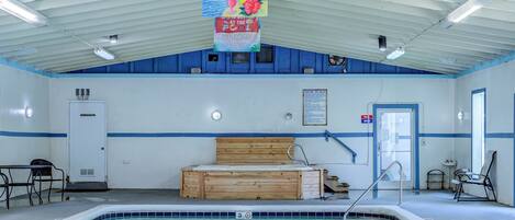 Una piscina interior con un banco de madera, un vestuario y una puerta.