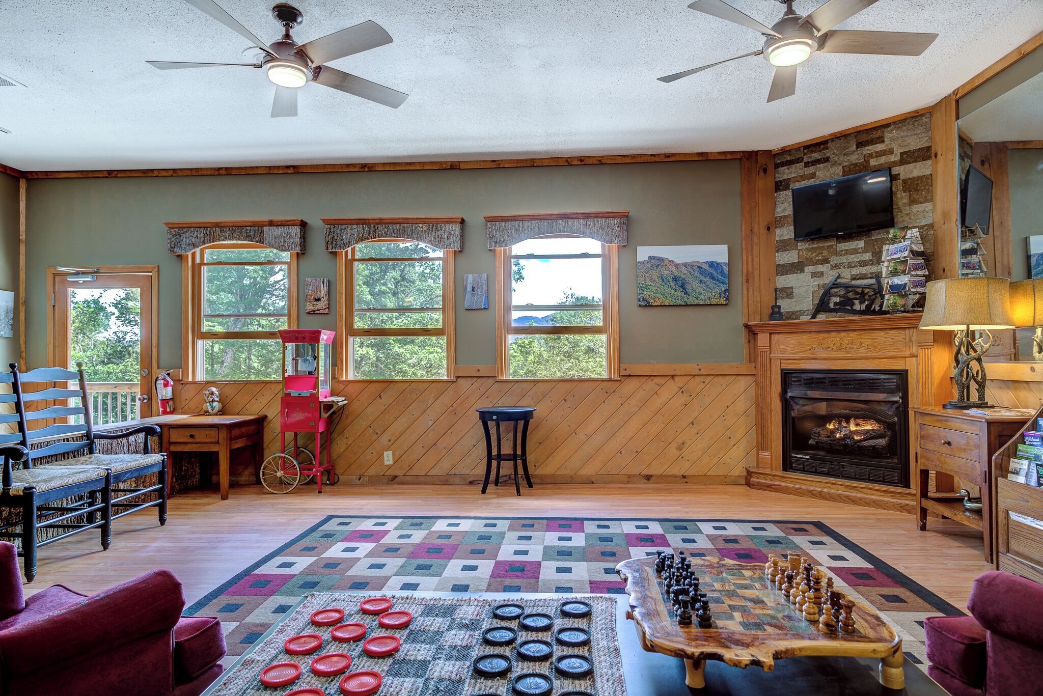Una sala de estar acogedora con chimenea, paredes de madera y ventanas amplias.