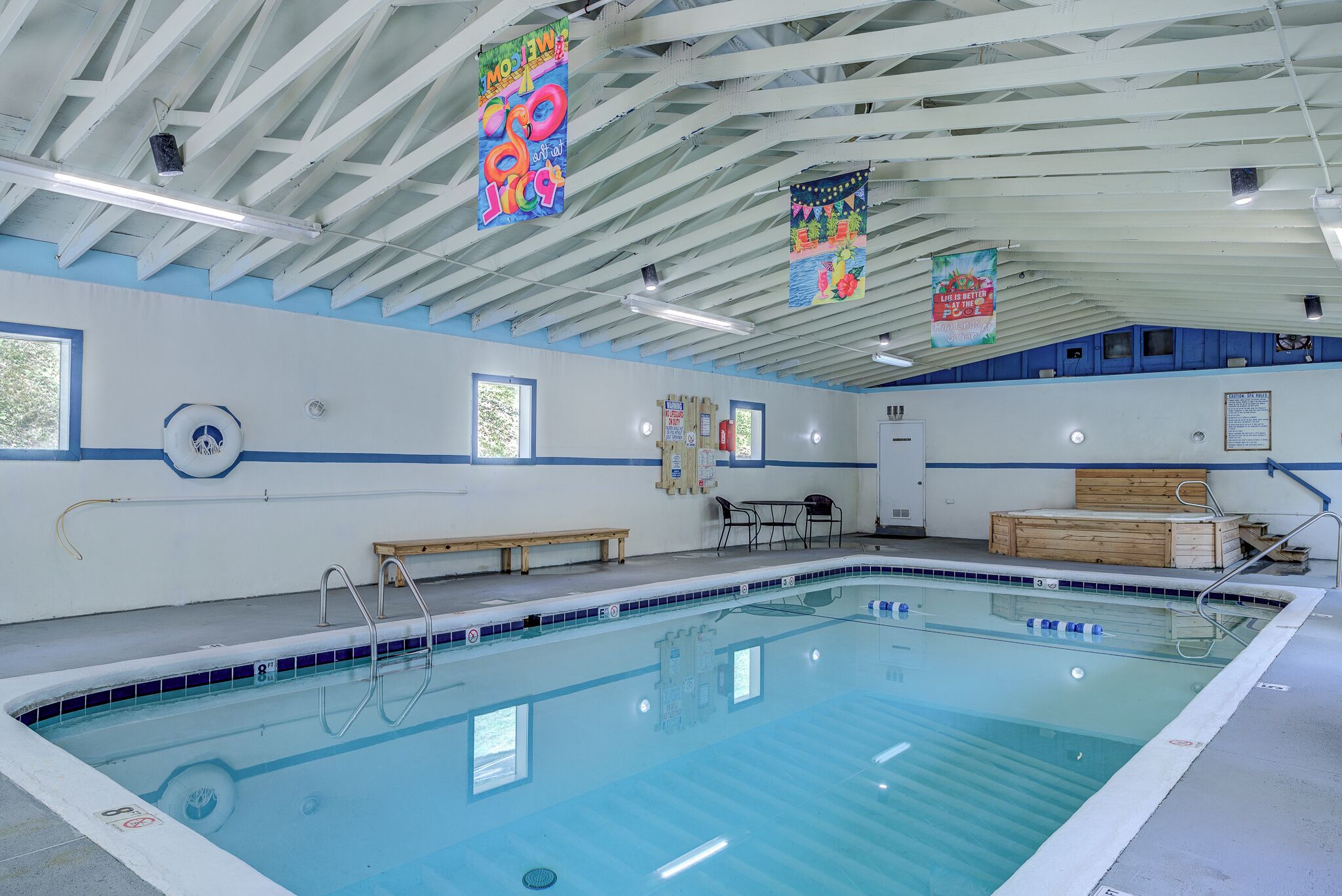 A swimming pool with a tiled edge, benches, and a wooden platform.