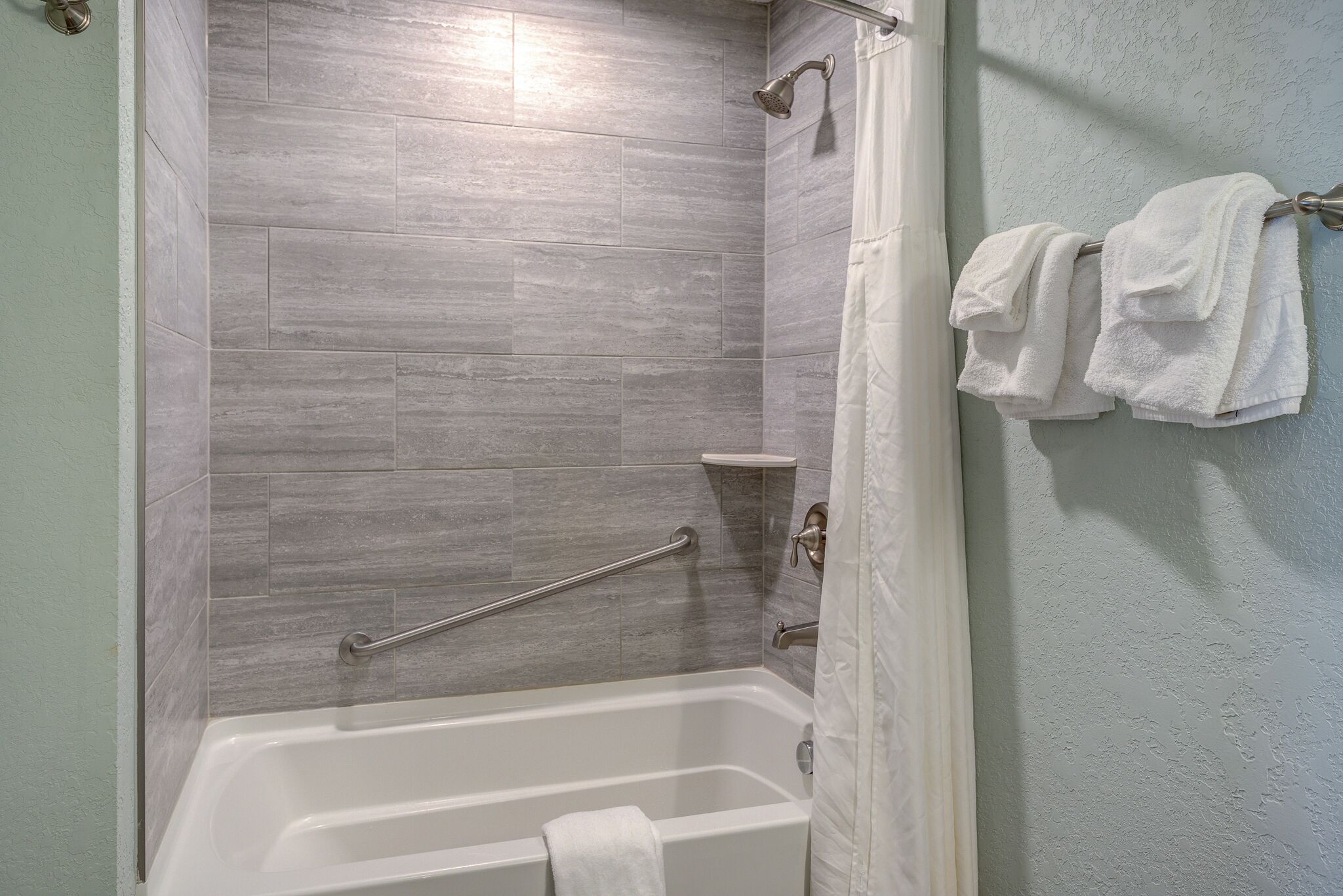 A bathroom with a bathtub, a shower, and a towel rack with towels.