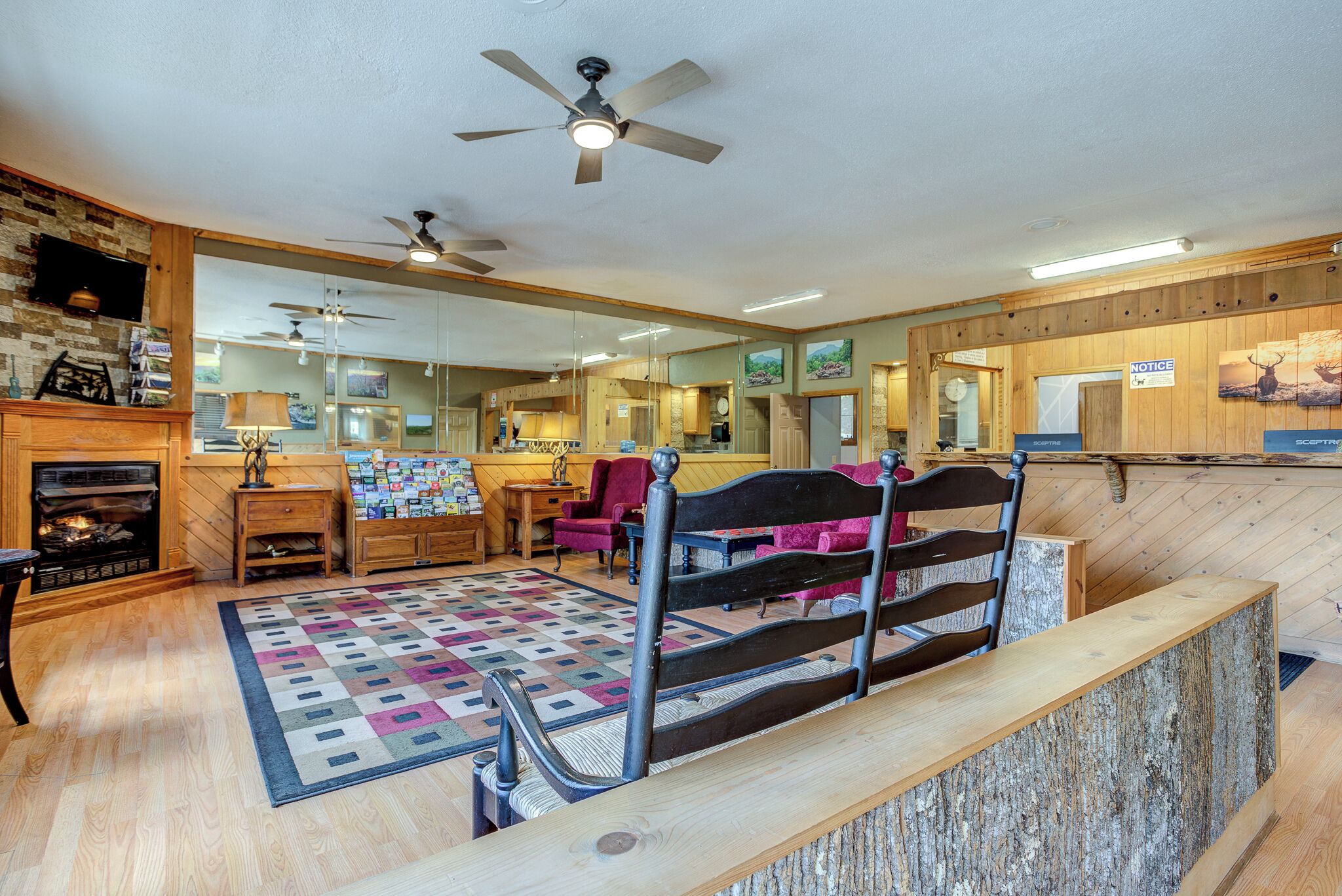 A cozy room with a fireplace, wooden furniture, a quilted rug, and a wooden reception desk.