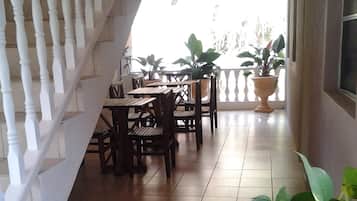 Un espace extérieur abrité, doté d’un escalier, de tables en bois, de chaises et de plantes en pot.