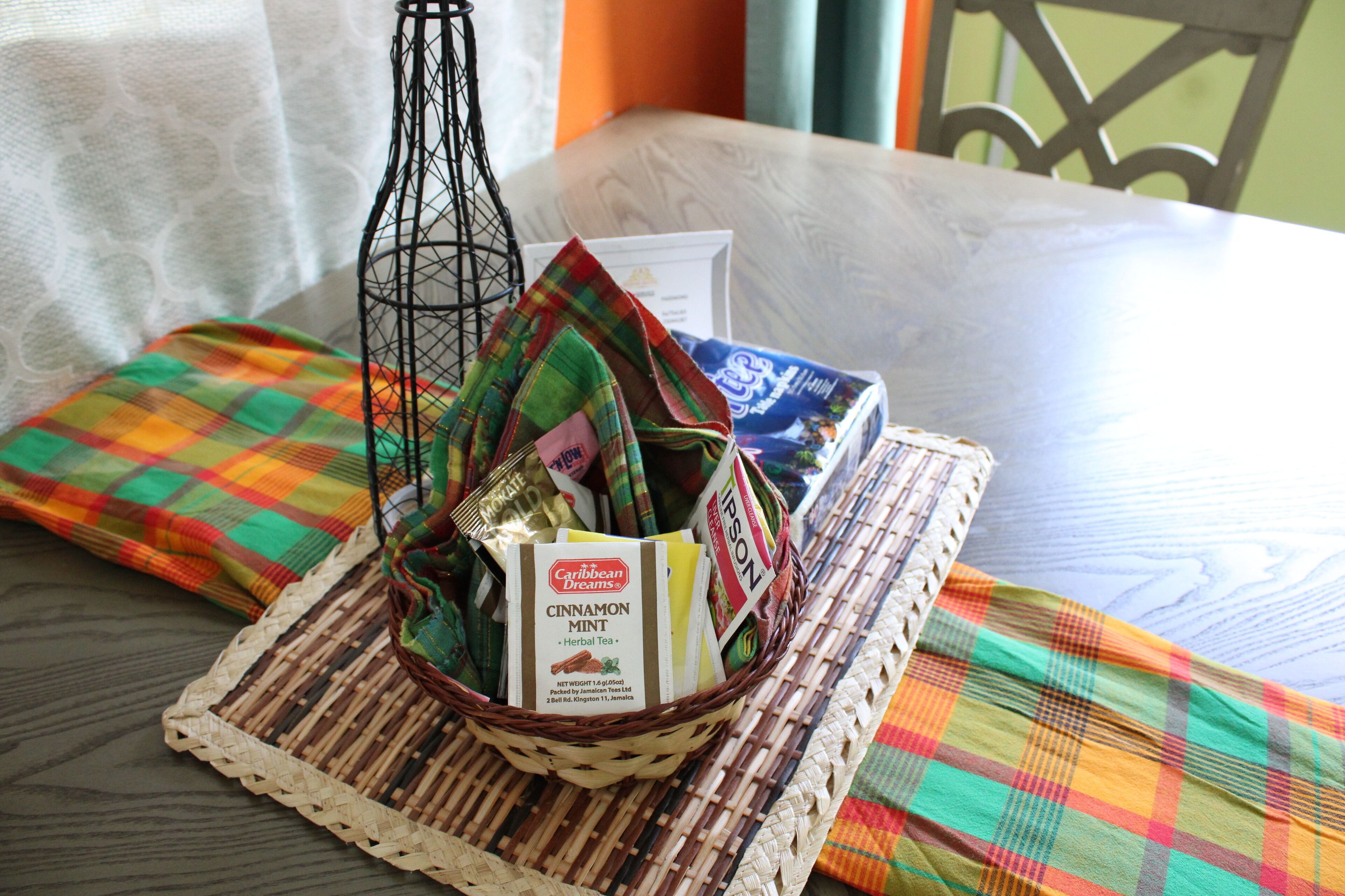A wicker basket with a label for 'Caribbean Dreams Cinnamon Mint Herbal Tea' on a woven placemat.