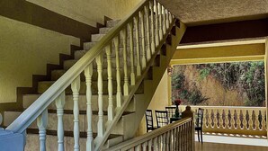 A staircase with white balusters leading to a landing area with a view of greenery outside.